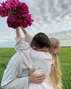 a man and woman hug each other in the middle of a field with pink flowers