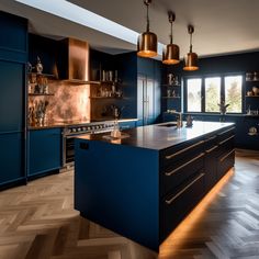 a large kitchen with blue cabinets and wood flooring, along with two pendant lights hanging from the ceiling