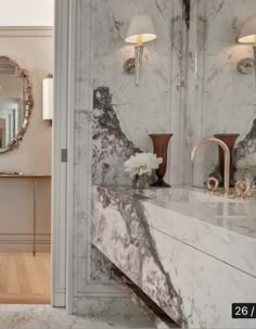 a bathroom with marble counter tops and white walls, along with a large mirror on the wall