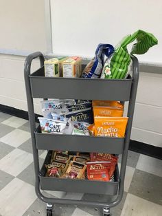 a grocery cart filled with snacks on top of a checkered tile floor next to a white wall