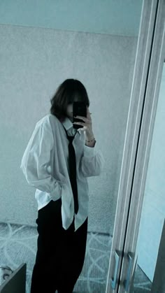 a woman taking a selfie in front of a mirror wearing a tie and shirt