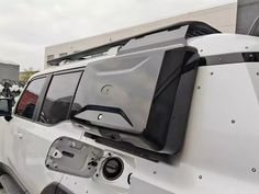 the back end of a white jeep parked in front of a building with its doors open