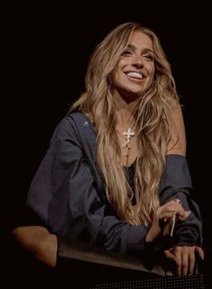 a woman with long blonde hair sitting in front of a keyboard and smiling at the camera