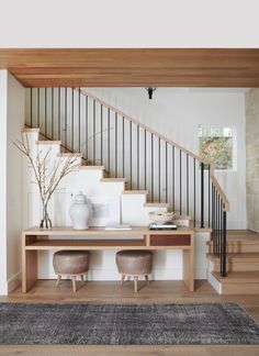 a staircase with two stools next to it and a table on the other side