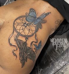 a woman's back with a butterfly and dream catcher tattoo on it