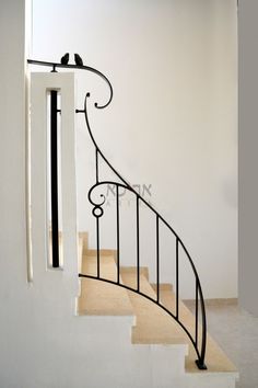 two birds sitting on the top of a stair rail in an empty room with white walls