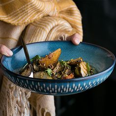 a woman holding a blue bowl filled with food