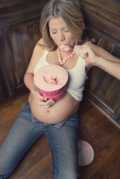 a pregnant woman sitting on the floor with a pink cupcake in her hand