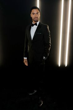 a man in a tuxedo is posing for a photo with lights behind him