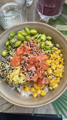 a bowl filled with different types of food on top of a table next to glasses