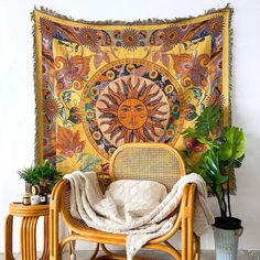 a chair with a blanket on it next to two plants and a potted plant