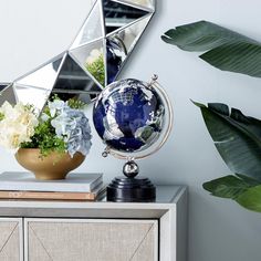 a blue and white globe sitting on top of a dresser next to a potted plant