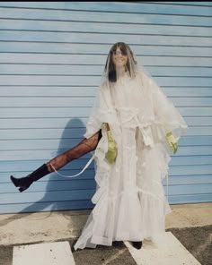 a woman in a white wedding dress and black boots is posing for the camera with her legs spread out