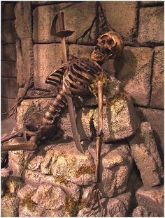 a skeleton sitting on top of a pile of rocks with a knife in it's mouth