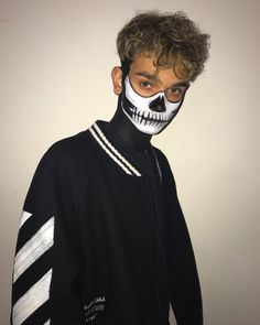 a young man with his face painted like a skeleton wearing a black jacket and white striped sweater