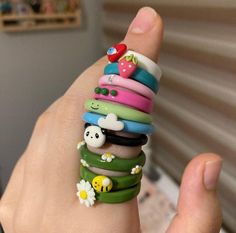 a person's hand holding a stack of bracelets with different designs on them