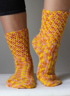 the legs of a woman wearing yellow and pink knitted socks with holes in them