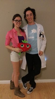 a man and woman standing next to each other in front of a wall with an apple on it