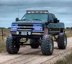 a large black truck driving down a dirt road