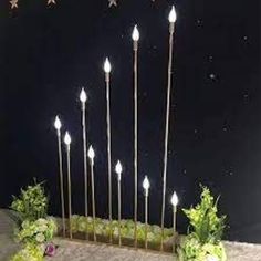 a group of candles that are sitting in the ground with flowers on it and stars above them