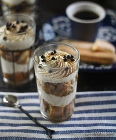 two glasses filled with dessert sitting on top of a table