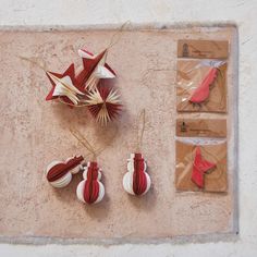 three red and white ornament hanging from strings on a beige wall next to brown envelopes