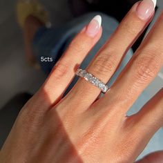 a woman's hand with a wedding ring on her finger and white nail polish