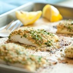 fish fillets on a pan with lemons and seasoning next to it, ready to be cooked