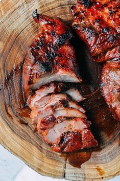 two pieces of meat sitting on top of a wooden plate