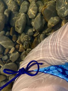 a person's leg with a blue ribbon tied around it and rocks in the background