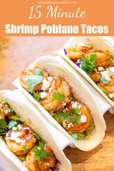 three shrimp tacos with cilantro and parsley on top, sitting on a wooden table