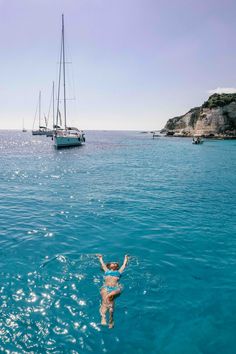 a person swimming in the ocean with boats in the background