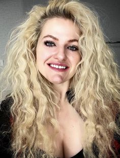 a woman with long blonde hair smiling for the camera