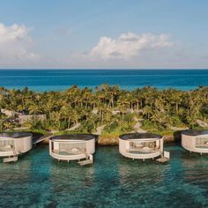 an aerial view of the ocean with several floating beds in front of palm trees and blue water