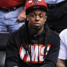 a man with dreadlocks and a red hat sitting in front of other people