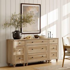 a wooden dresser sitting next to a table with a vase and bowl on top of it