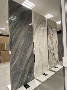 three glass partitions in the middle of a room with marble walls and flooring