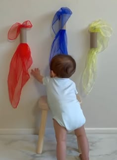 a small child is playing with some colorful items on the wall behind him and holding onto one of them's legs