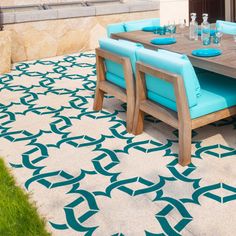 an outdoor dining table and chairs with blue cushions on the outside patio, next to grass