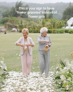 two older women standing in the grass with flowers