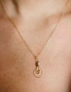 a close up of a person wearing a gold necklace with a knot on the end