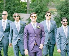 a group of men in suits and sunglasses standing next to each other on the grass