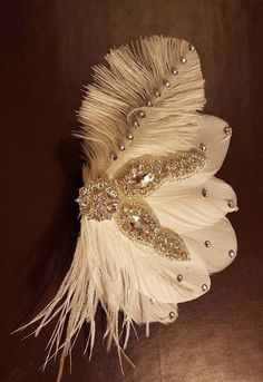 a white feather and beaded brooch on a brown leather background with gold accents