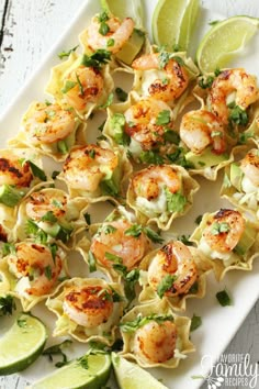 shrimp and tortilla shells with lime wedges on a white platter, ready to be served