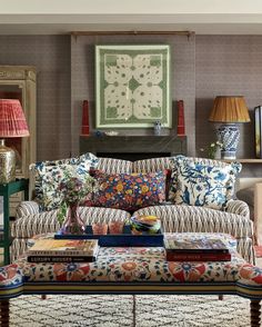 a living room filled with lots of furniture and pillows on top of a table in front of a fire place