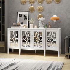 a white cabinet sitting in front of a gray wall with gold circles hanging above it