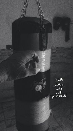 a hand holding onto a punching bag with the words in arabic and english on it