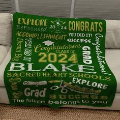 a green blanket that has words all over it on top of a couch in a living room