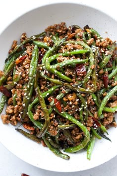 a white bowl filled with green beans and meat