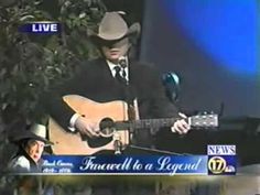 a man in a cowboy hat playing a guitar and singing into a microphone on the news